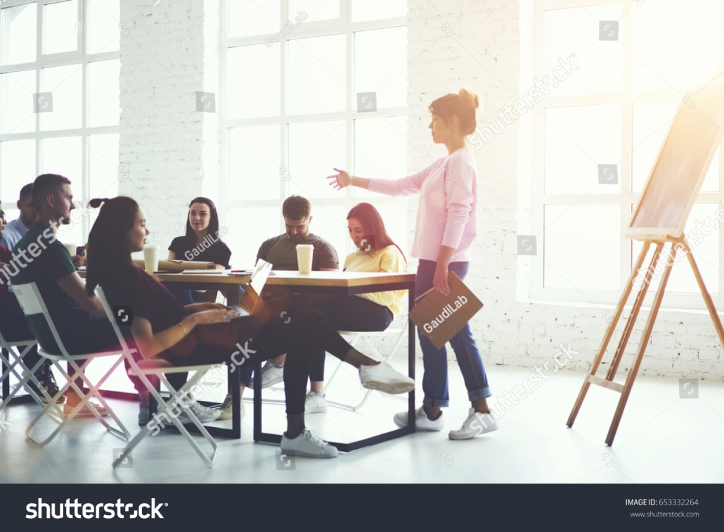 stock-photo-male-and-female-creative-students-listening-explanation-of-female-train-manager-during-workshop-653332264